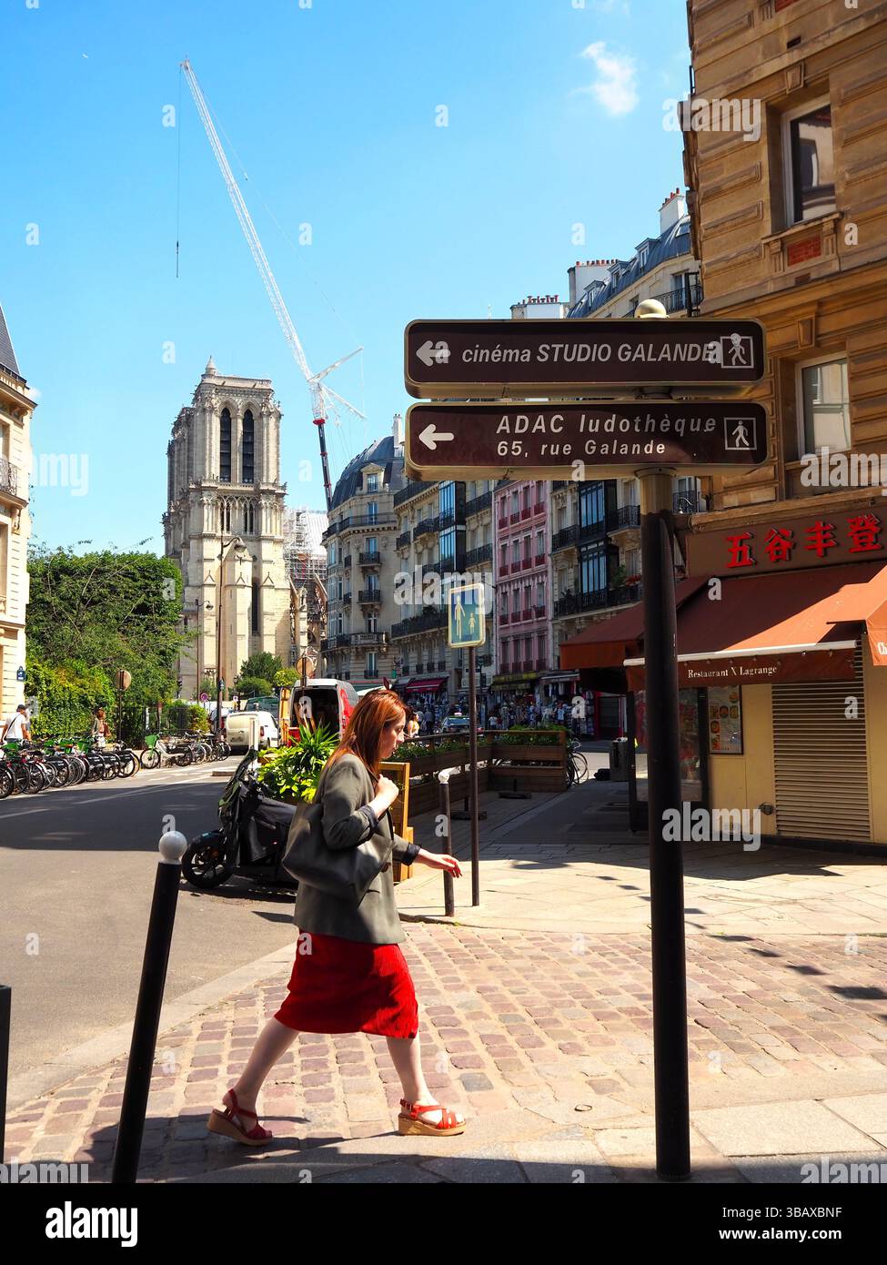 Notre-Dame wird restauriert von einer Pariser Straße aus mit einer Frau in einem roten Rock, im Sommer in Paris Stockfoto