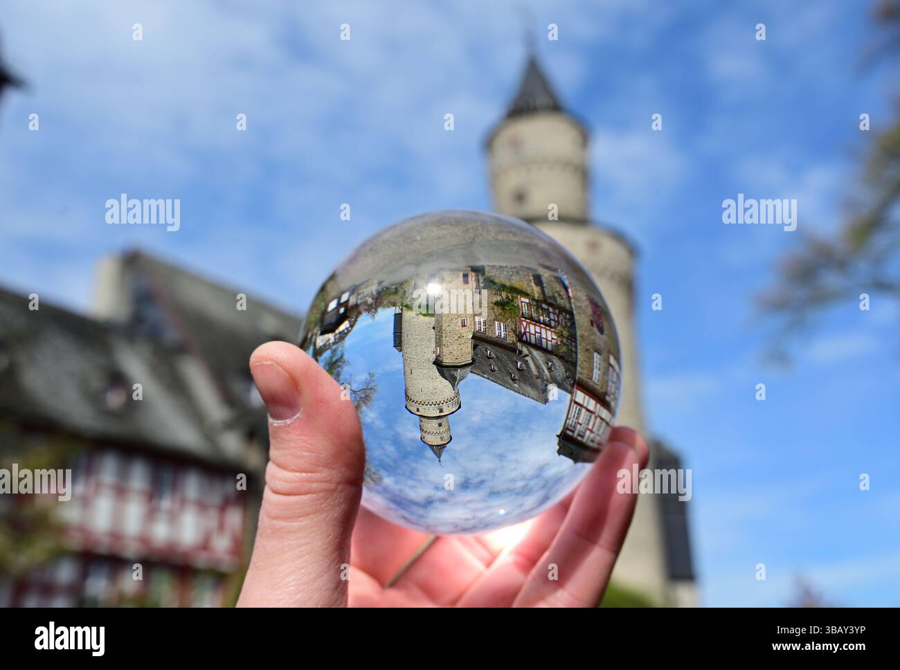 Hand mit der Objektivkugel, durch die das alte Fachwerkhaus in Idstein fotografiert wurde, Deutschland Stockfoto