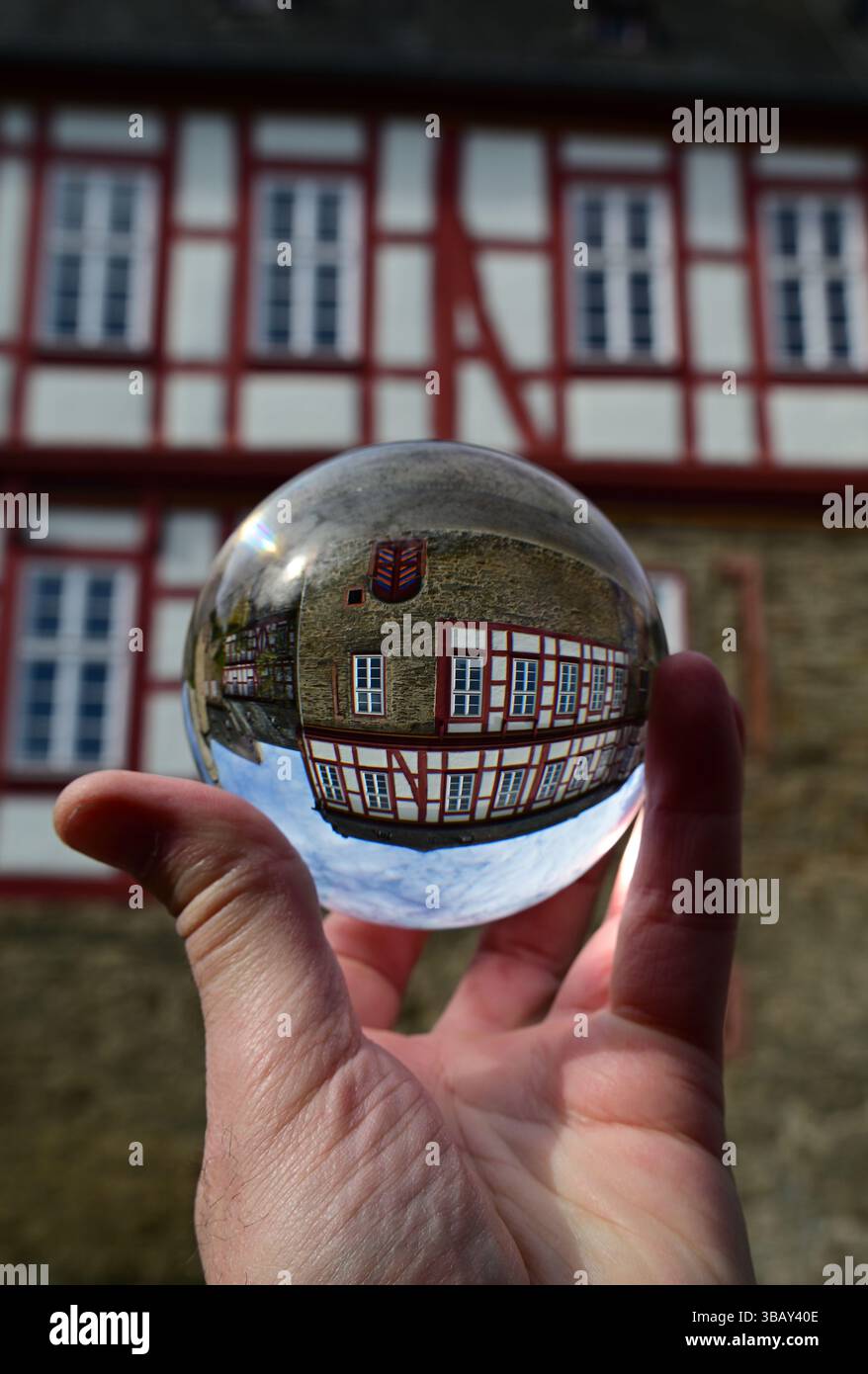 Hand mit der Objektivkugel, durch die das alte Fachwerkhaus in Idstein fotografiert wurde, Deutschland Stockfoto