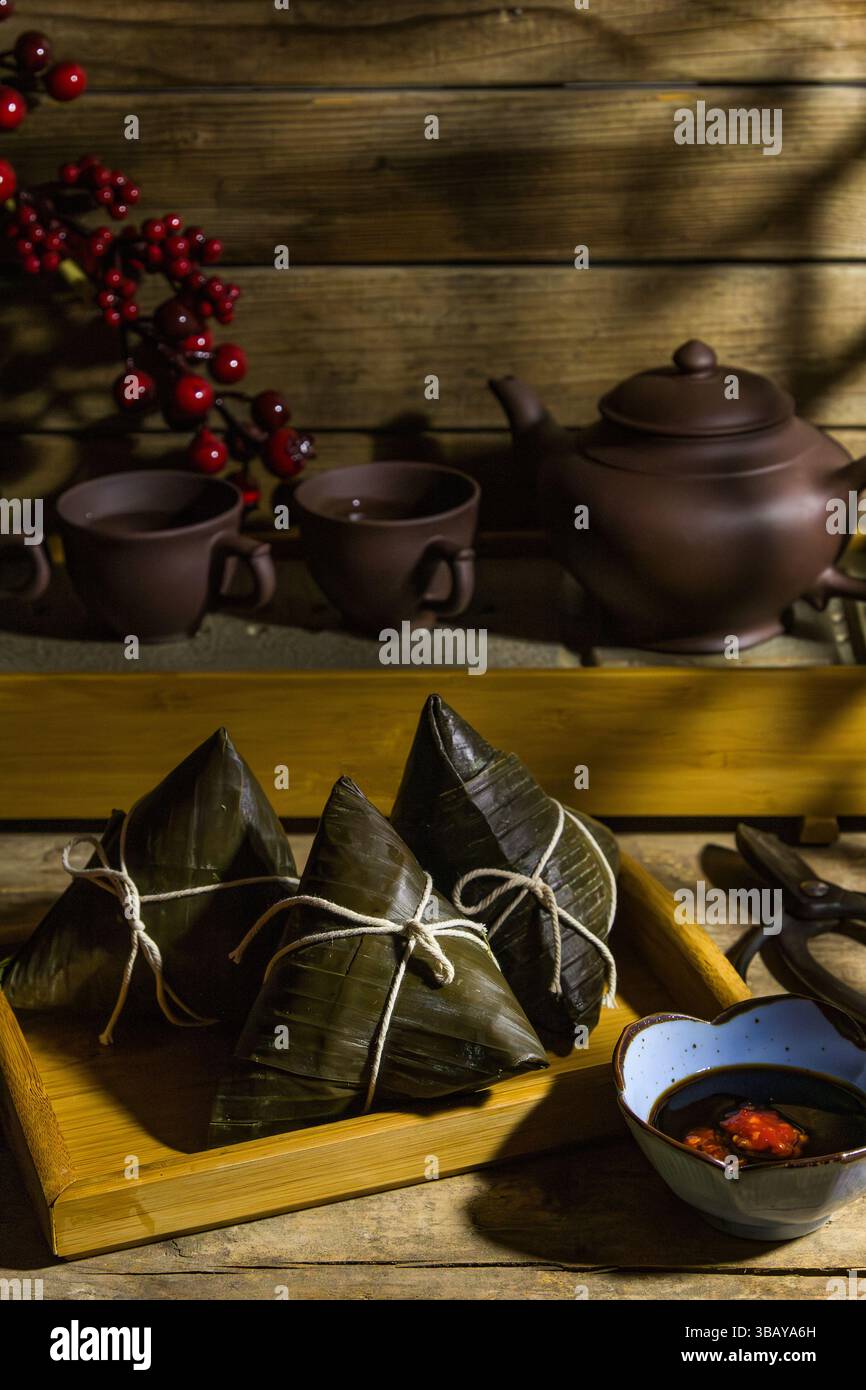 Reisknödel Zongzi im Dampfkorb mit Tee-Set - traditionelle süße chinesische Gerichte auf einem Teller für Drachenboot Duanwu Festival Feiern Stockfoto