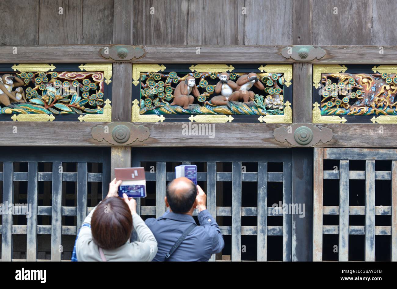 BESUCHER fotografieren die berühmten Schnitzereien der ‚Sprich nichts Böses, sieh nichts Böses, höre nichts Böses‘-Affen im zum UNESCO-Weltkulturerbe gehörenden Toshogu-Schrein in Nikko, Japan Stockfoto