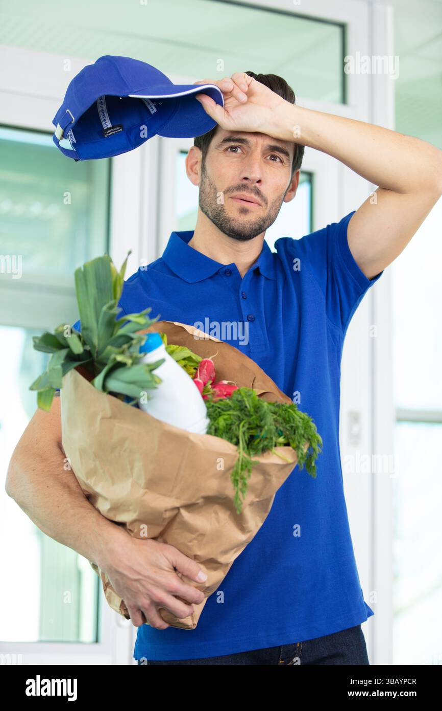Müder männlicher Kurier, der Lebensmittel bestellt Stockfoto