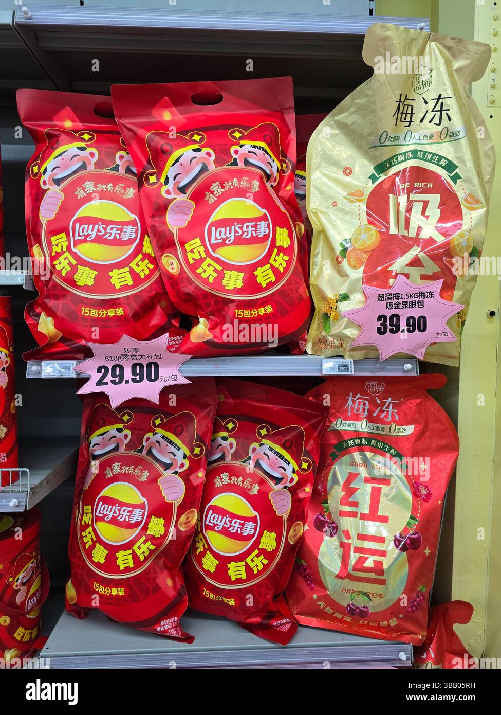 Farbenfrohe Geschenkboxen für das chinesische Neujahrsfest von Lay in Supermarktregeln, dekoriert mit festlichen Löwentanz-Maskottchen und Preisschildern. Stockfoto