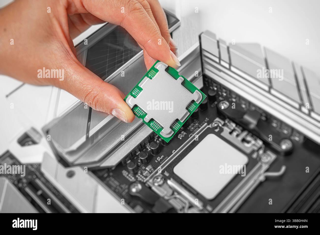 Eine Person hält einen Computerprozessor vorsichtig über einen Sockel auf der Hauptplatine Stockfoto