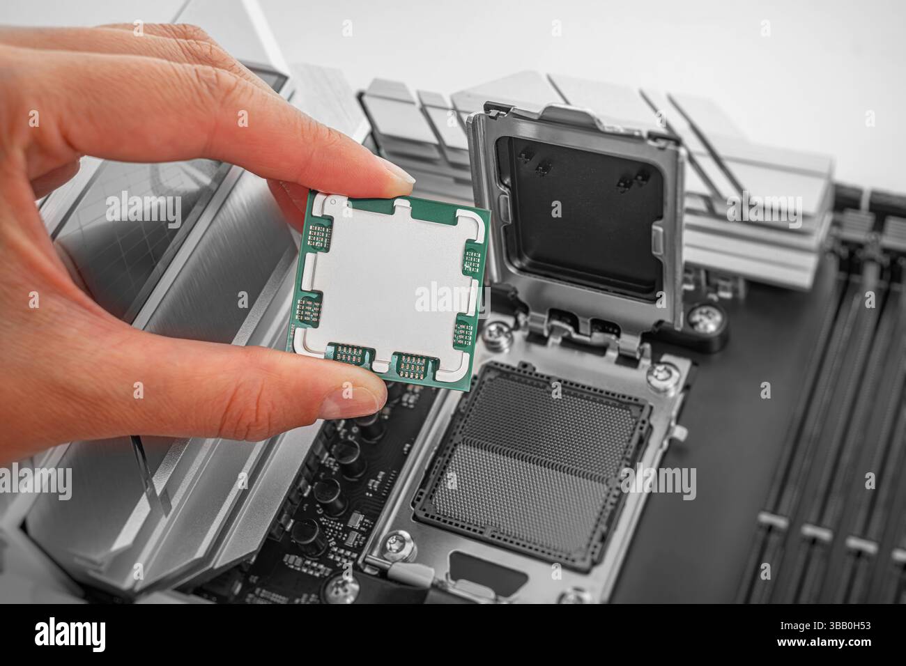 Eine Person hält einen Computerprozessor vorsichtig über einen Sockel auf der Hauptplatine Stockfoto