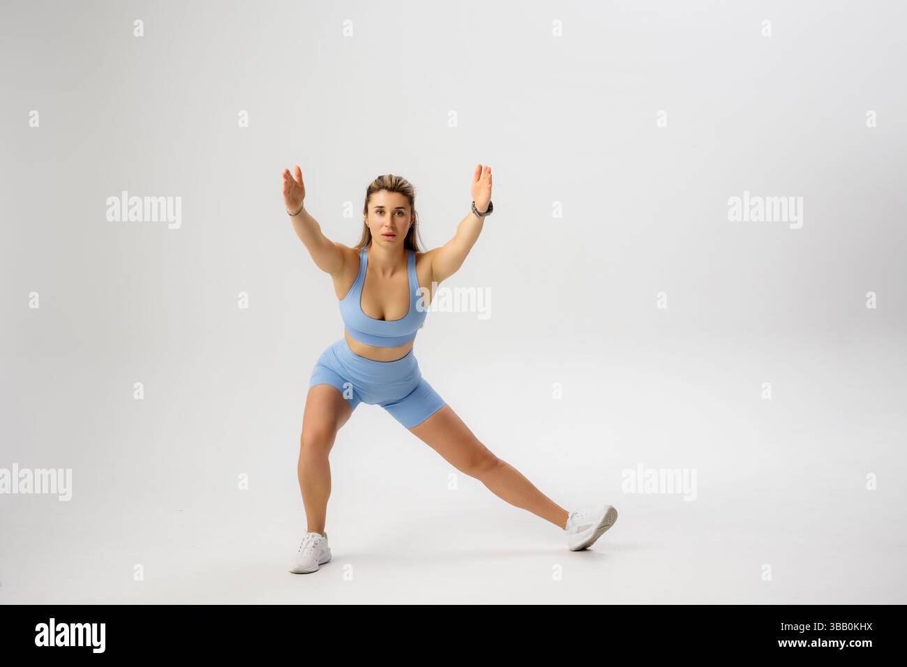 Fitness-Modell, das während einer Fitnesssitzung in einem Studio einen dynamischen seitlichen Ausfallschritt durchführt Stockfoto