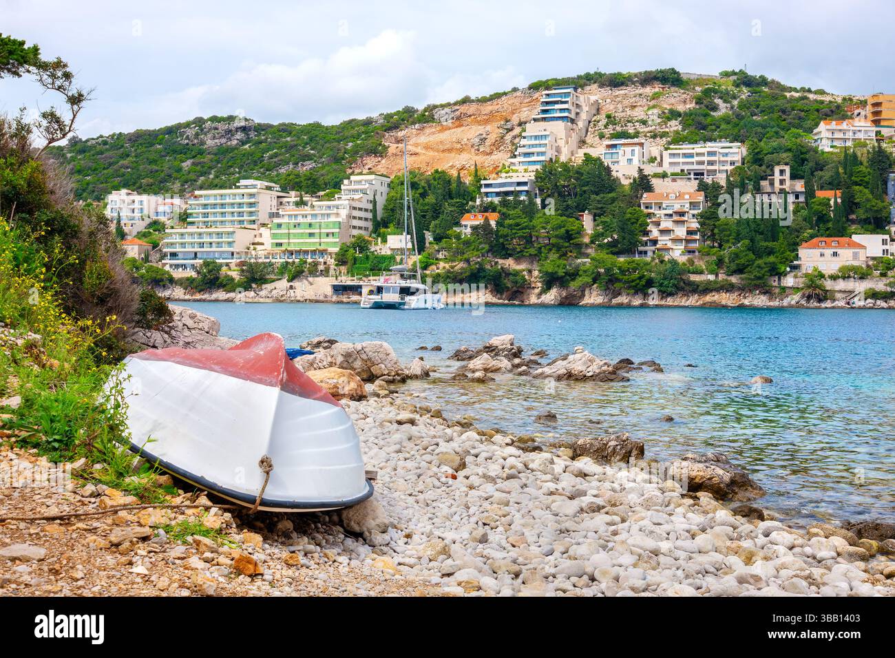 Weißes Boot ruht an den felsigen Ufern der Bucht von Lapad. Dubrovnik, Kroatien Stockfoto