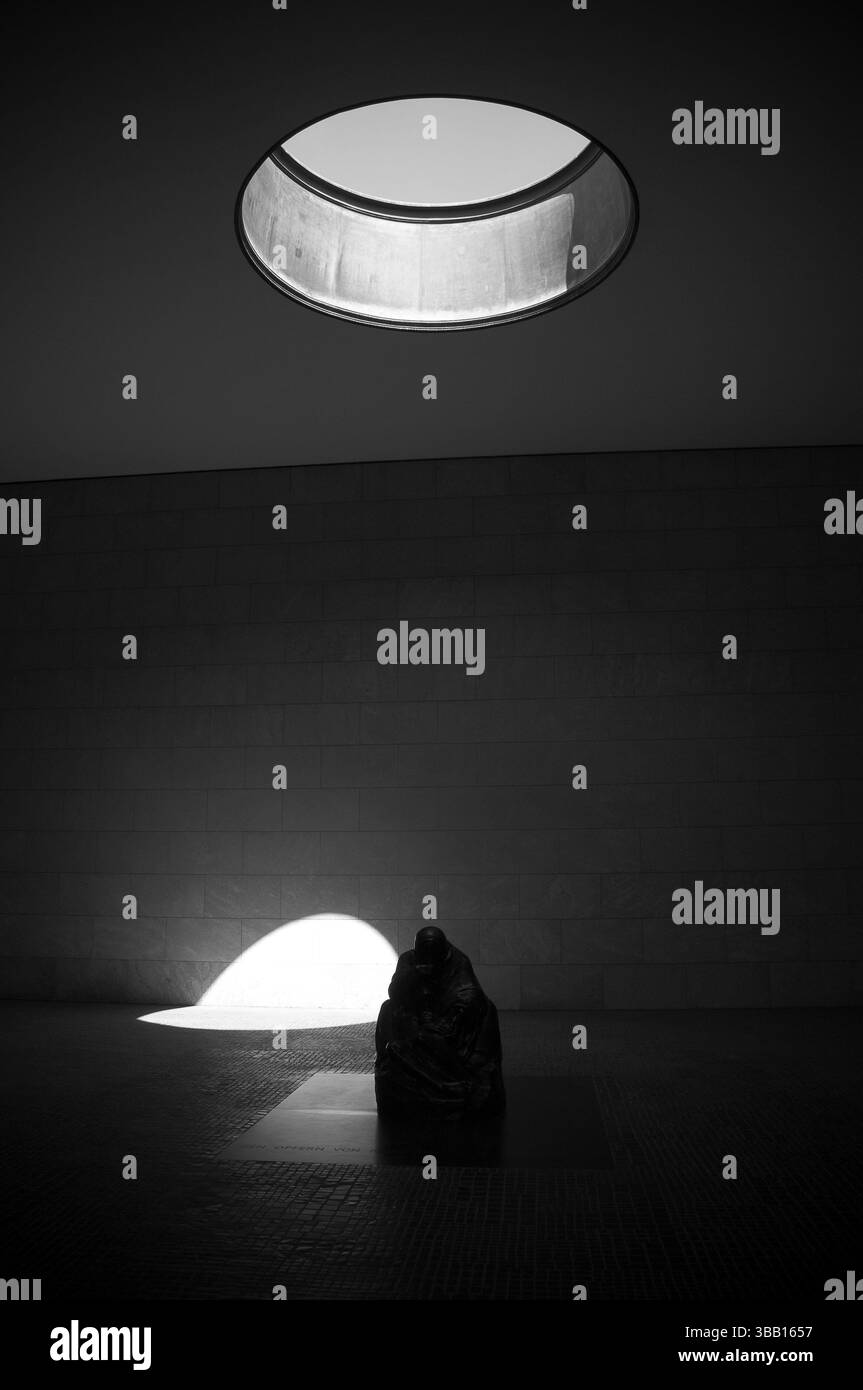 Eine einsame Skulptur sitzt unter einem runden Oberlicht und wirft faszinierende Schatten in einen architektonischen Raum in Berlin. Stockfoto