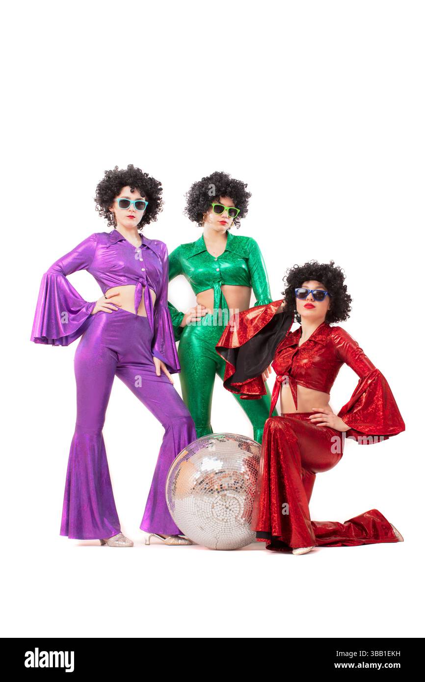 Drei weibliche Popstars in Neonkleidung posieren vor einer silbernen Kugel. Die Frauen tragen bunte Kleidung und Sonnenbrillen im Stil der 80er Jahre. Stockfoto