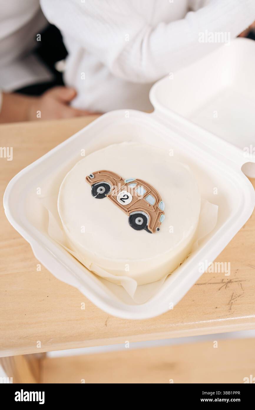 Kleiner bento-Kuchen. Mit einem Auto. Süßer Mini-Kuchen für den Geburtstagskind. Glasierter Kuchen in einer Schachtel. Stockfoto