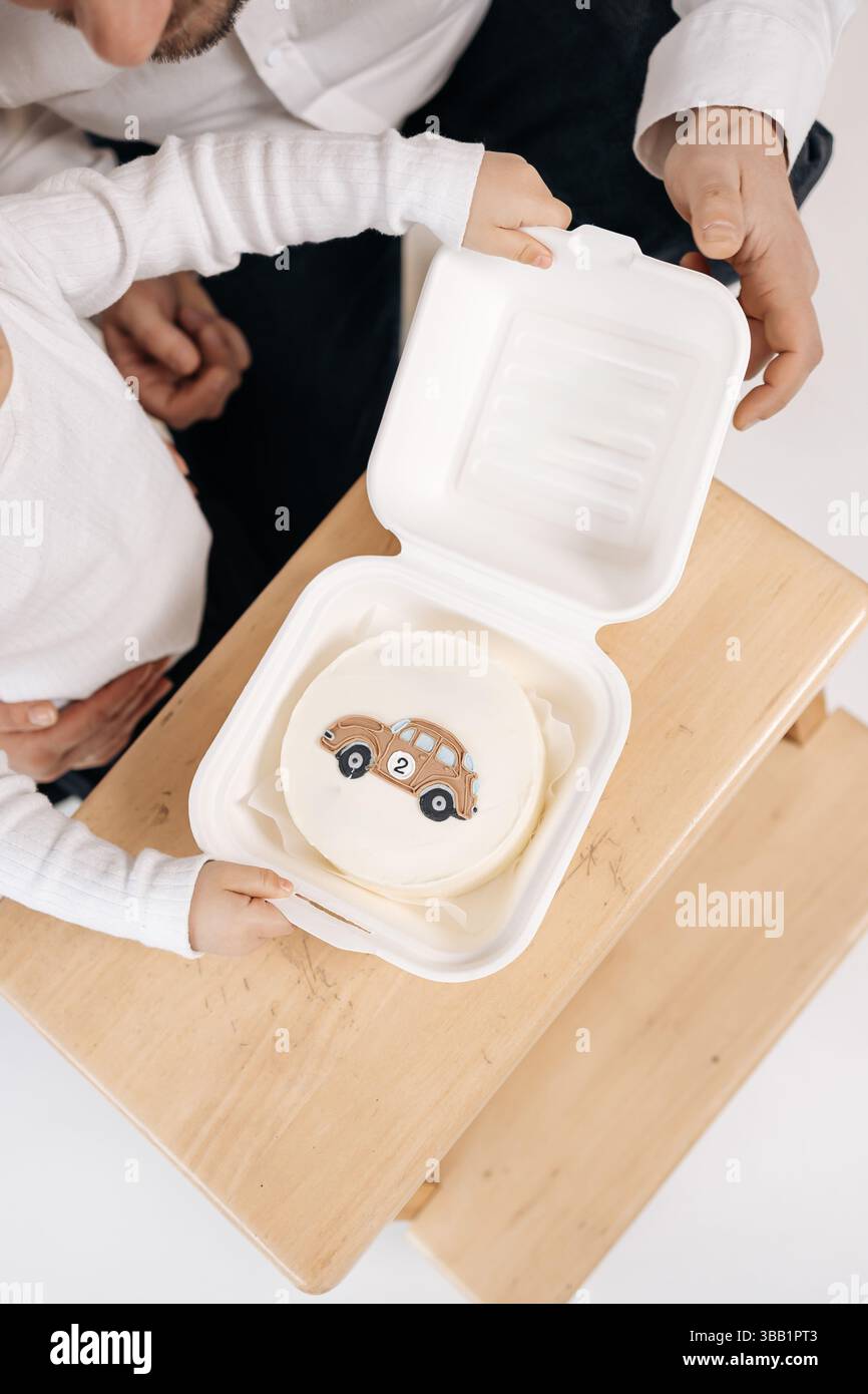 Kleiner bento-Kuchen. Mit einem Auto. Süßer Mini-Kuchen für den Geburtstagskind. Glasierter Kuchen in einer Schachtel. Stockfoto