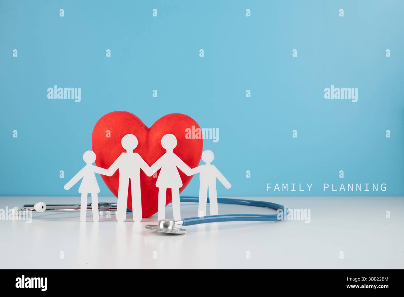 Eine vierstellige Papierausschnittfamilie vor einem roten Herzen und einem Stethoskop, auf blauem Hintergrund mit dem Text „FAMILIENPLANUNG“ auf der rechten Seite. Stockfoto