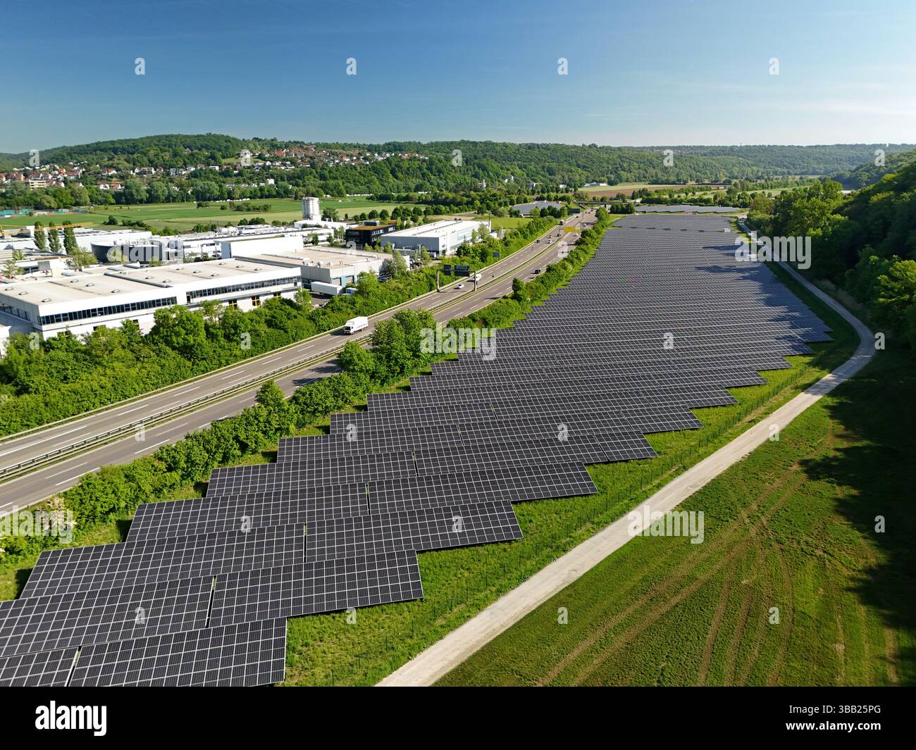 Luftdrohnenfoto einer großen Reihe von Photovoltaik-Solarpaneelen neben der Autobahn Stockfoto