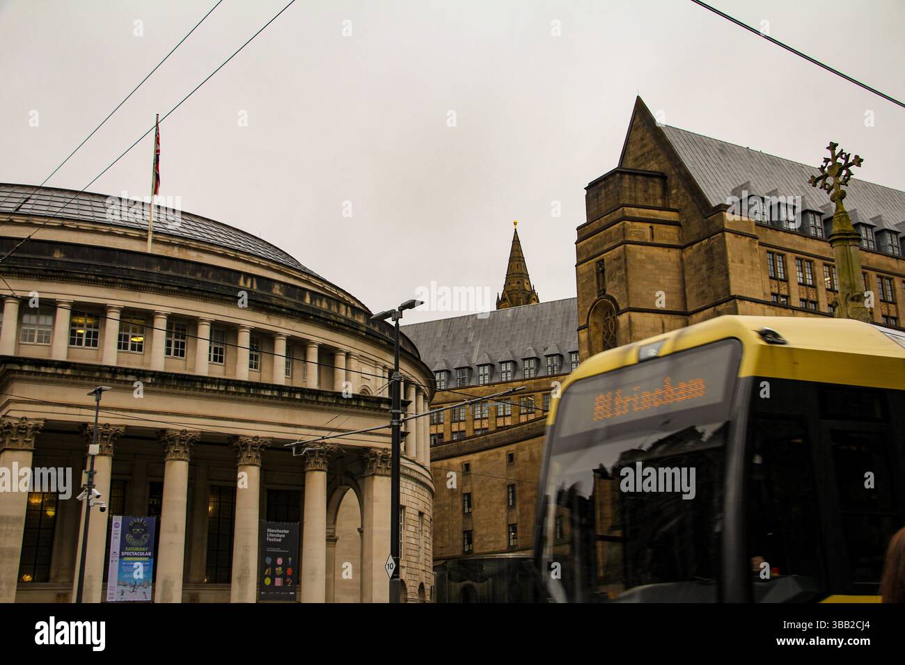 Das ikonische Äußere der Manchester Central Library, umrahmt von gotischer Architektur und öffentlichen Verkehrsmitteln an einem bewölkten Tag im Stadtzentrum. Stockfoto