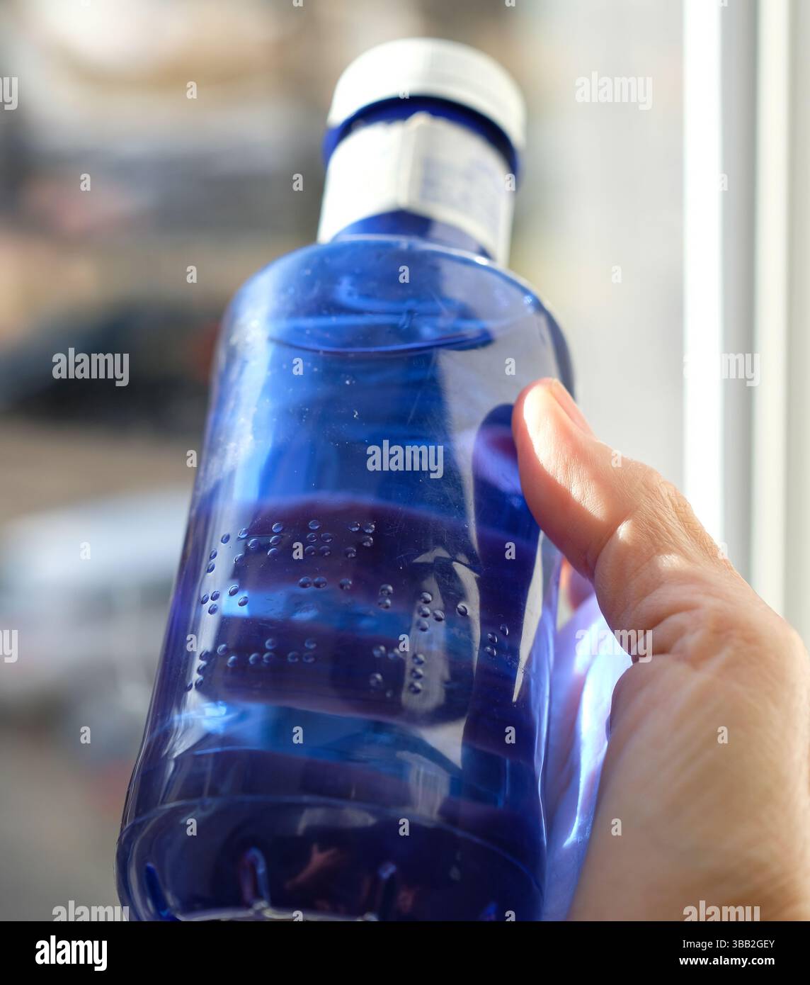 Schrift in Brailleschrift auf einer Plastikflasche. Erhöhte Punkte auf der Plastikflasche. Person liest Braille. Lesen Sie mit den Fingern. Brailleschrift für Kunststoff. Stockfoto