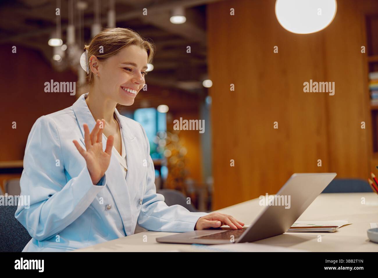 Eine junge Geschäftsfrau, die aktiv an einem virtuellen Meeting in einer modernen Arbeitsumgebung teilnimmt Stockfoto