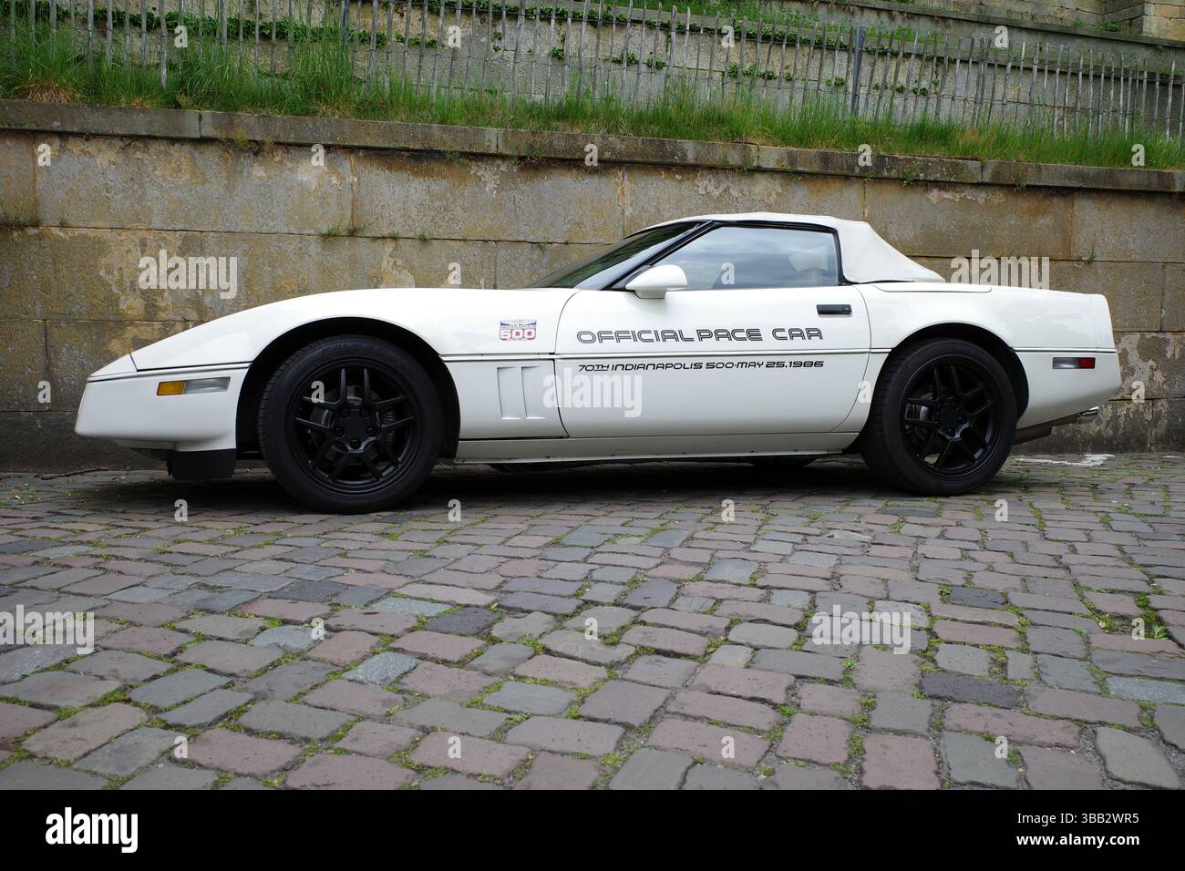 Bad Bentheim, Deutschland - 4. Mai 2025 Eine weiße Chevrolet Corvette C4 steht neben einer alten Mauer. Es war ein offizieller Pace Car Indianapolis im Jahr 1986 Stockfoto