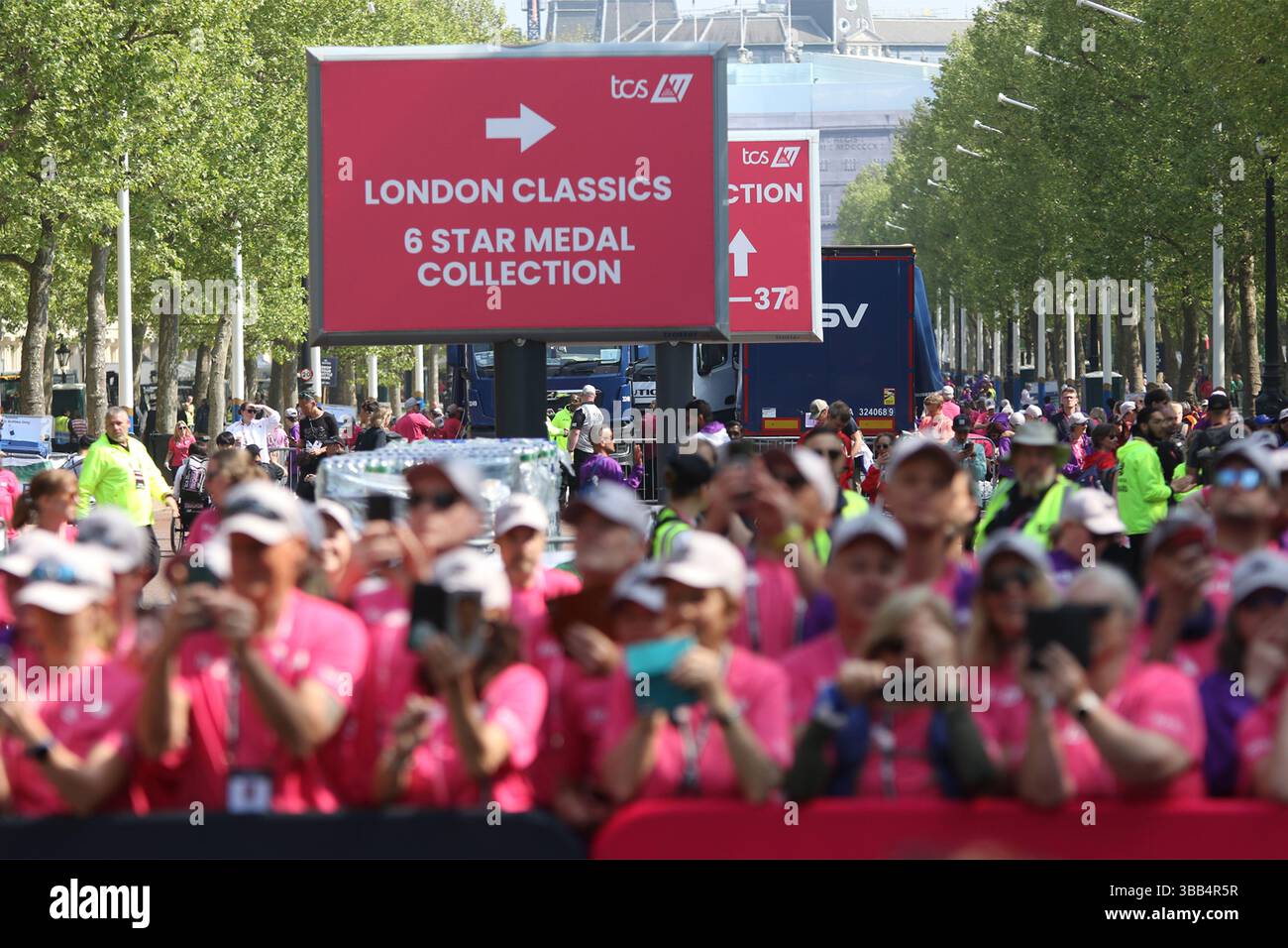 Mitarbeiter und Beamte versammeln sich, um beim TCS London Marathon 2025 in der Mall die offiziellen Finisher-Medaillen zu verteilen Stockfoto