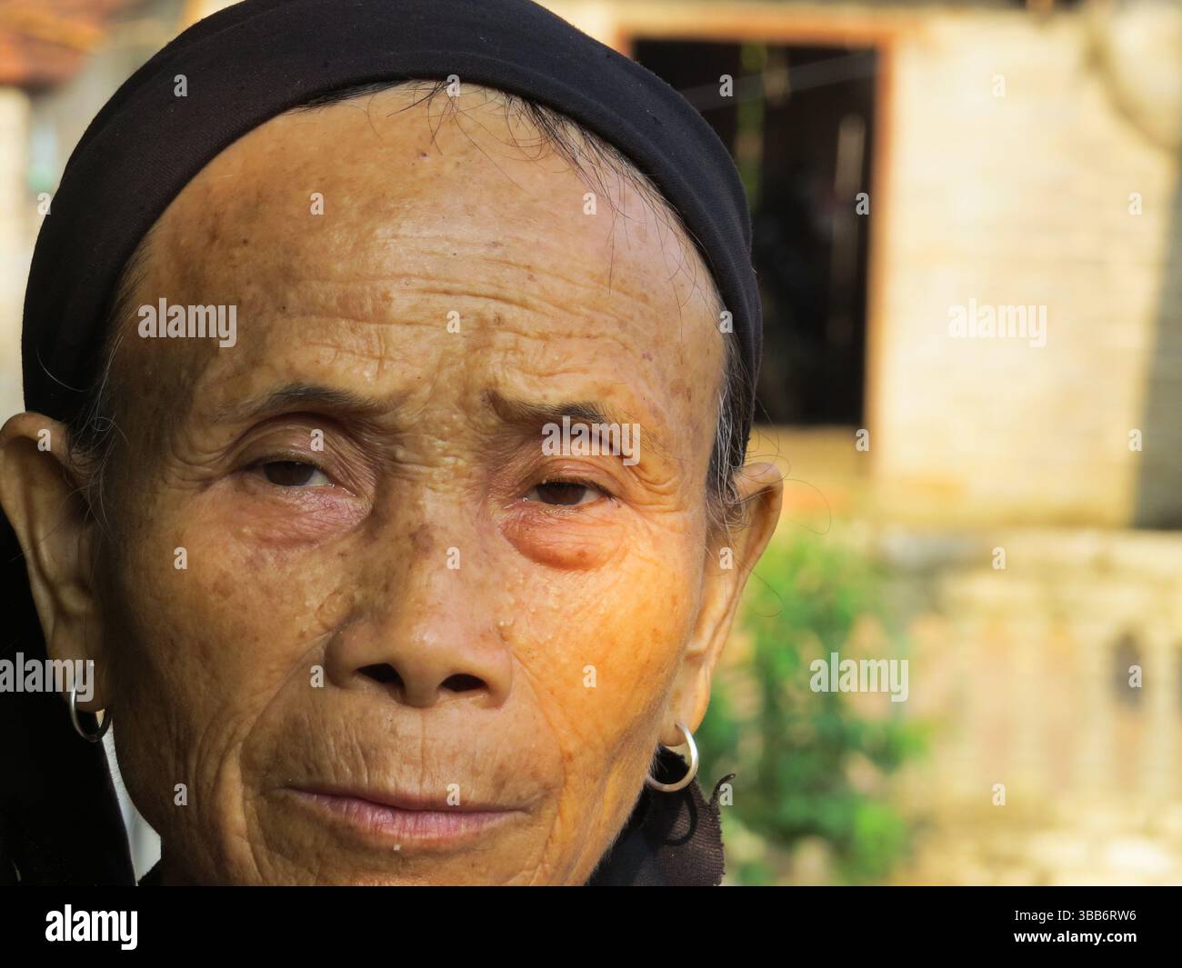 Eine ältere vietnamesische Frau, die ein traditionelles schwarzes Kopftuch und silberne Ohrringe trägt, wurde im Dorf Bac Son in der Provinz lang Son in Vietnam gefangen genommen Stockfoto