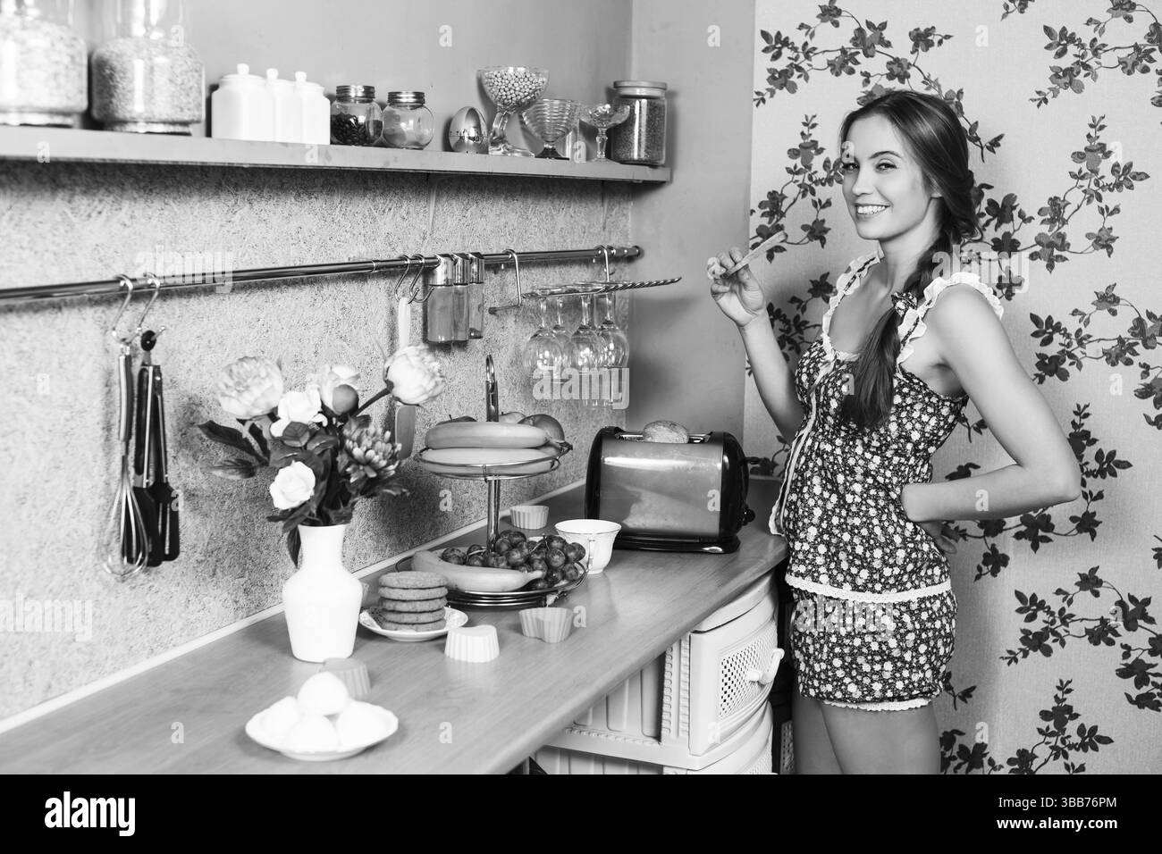 Attraktive Hausfrau, die in ihrer Küche Toast isst Stockfoto