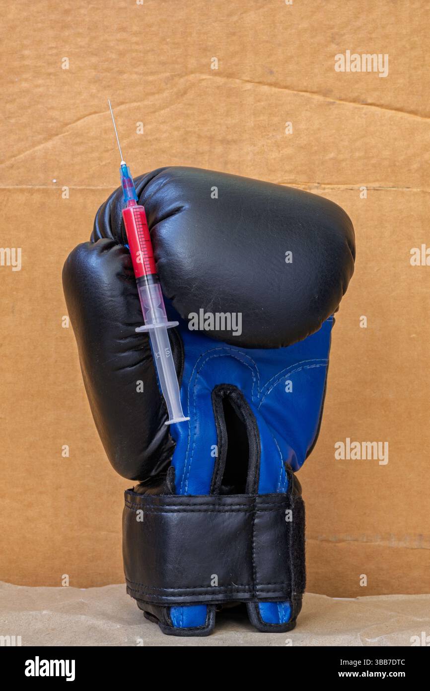 Vertikale Aufnahme einer blauen Boxhandschuhspritze mit roter Flüssigkeit auf Kartonhintergrund Stockfoto