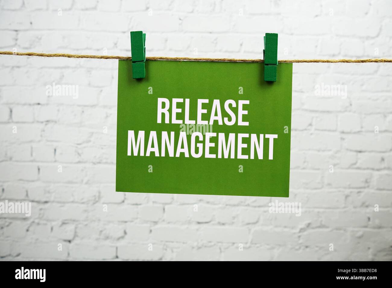 Text des Release Management auf grüner Papierkarte, die mit einem Seil auf weißem Backstein hängt Stockfoto