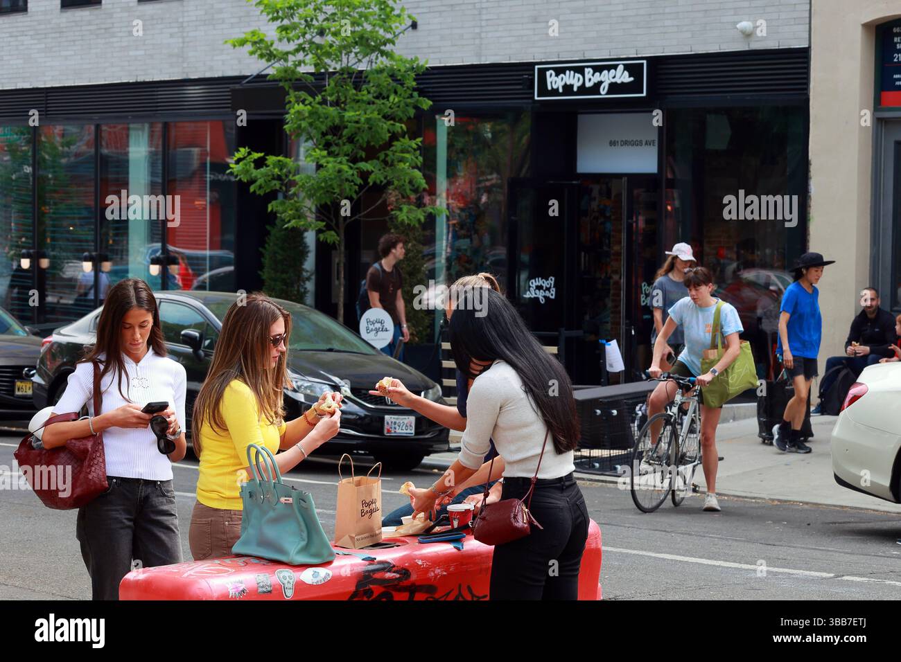 Leute teilen sich einen Bagel vor Popup Bagel, 661 Driggs Ave in Brooklyns Williamsburg Nachbarschaft. Stockfoto