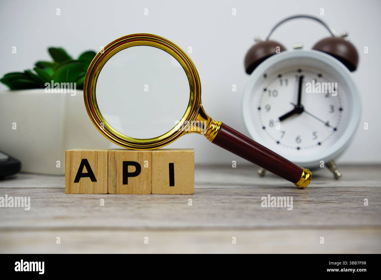 Lupe und Wecker mit Holzblöcken Alphabet Buchstaben API-Textnachricht auf hölzernem Hintergrund Stockfoto