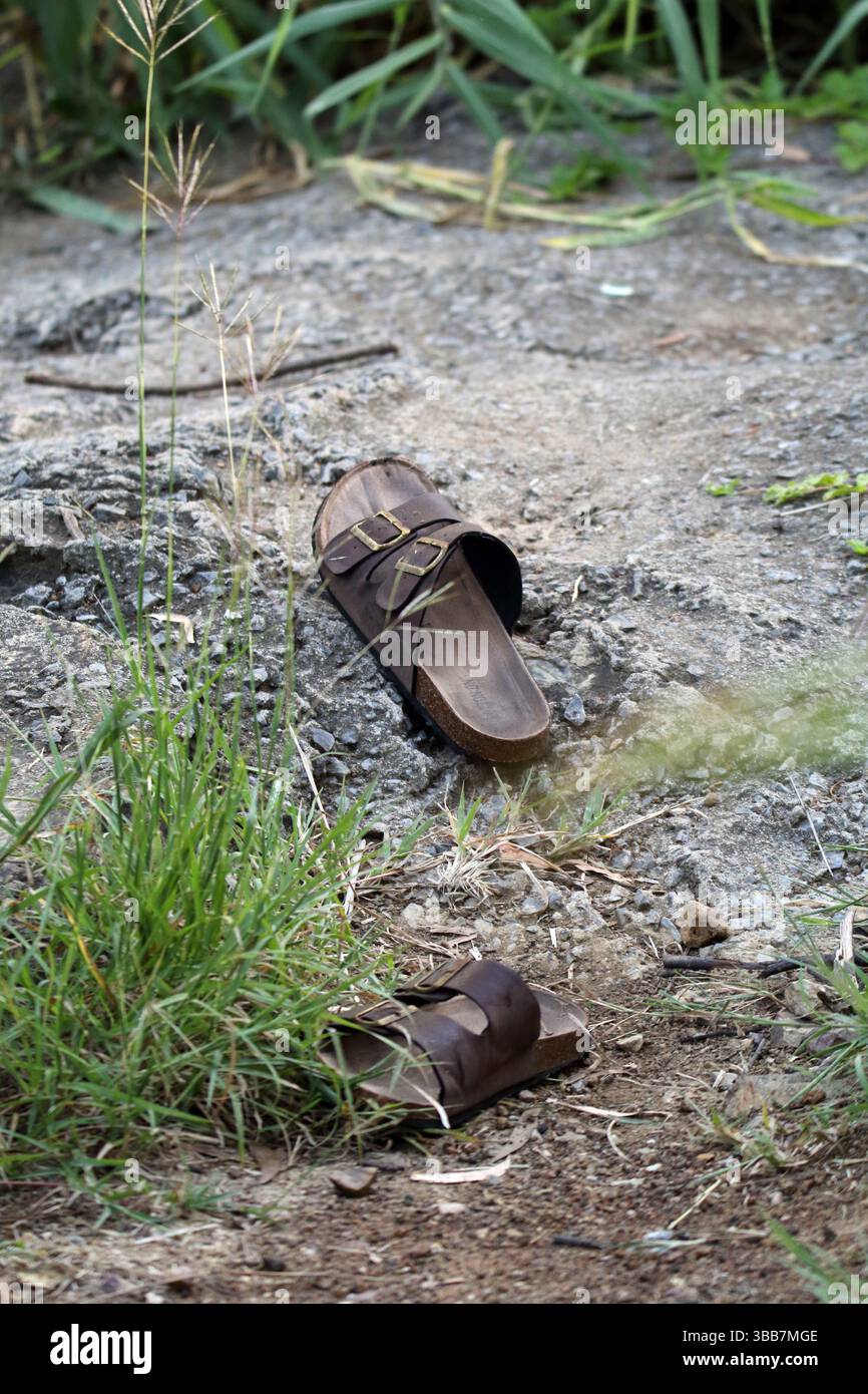 Verlassene Schuhe in einem Park mit Gras und Zement Stockfoto