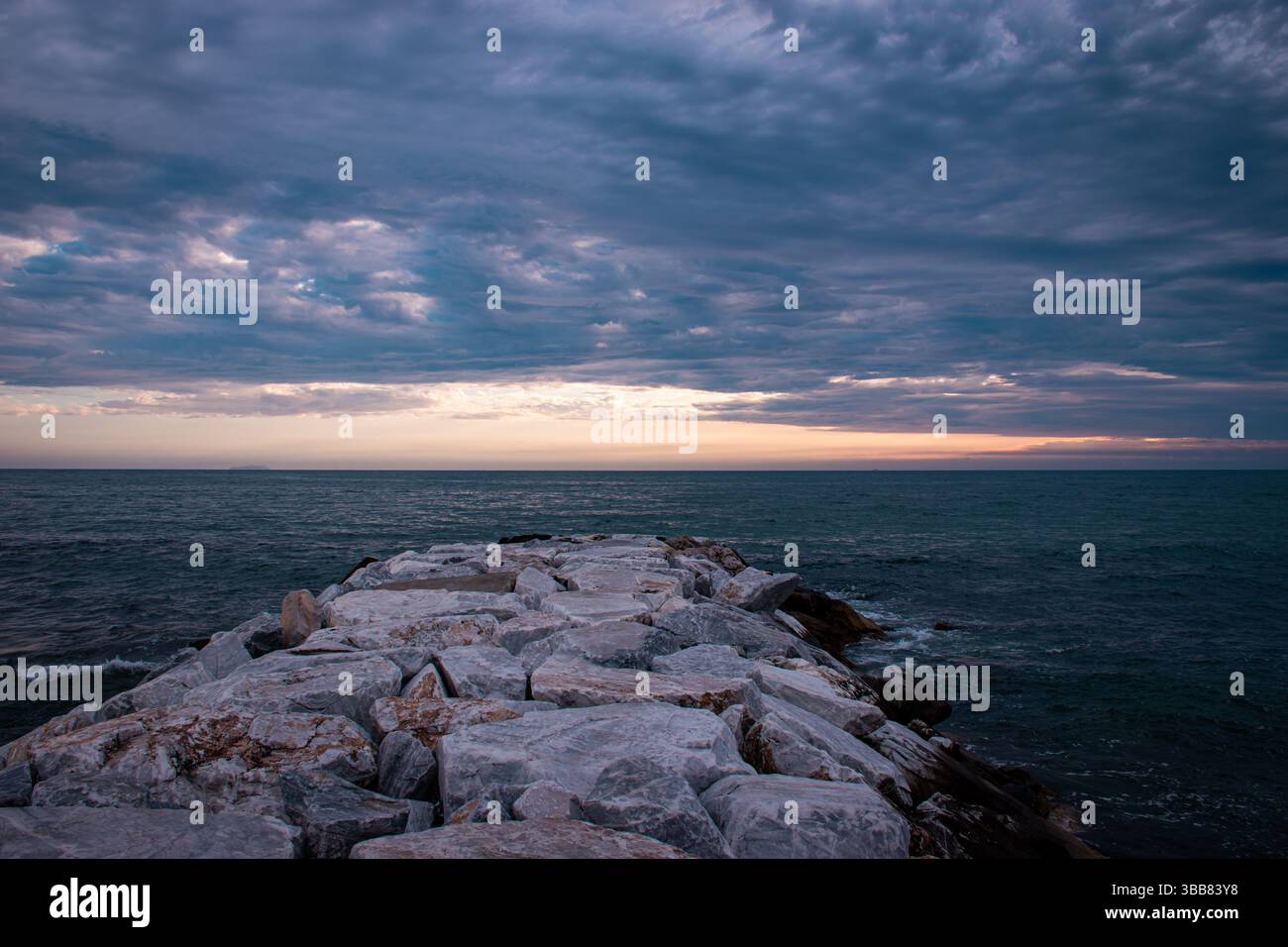 Frühlingsblick auf das Meer in Marina di Pisa unter einem bewölkten Sonnenuntergangshimmel, mit zarten Farben und einer ruhigen Atmosphäre. Stockfoto