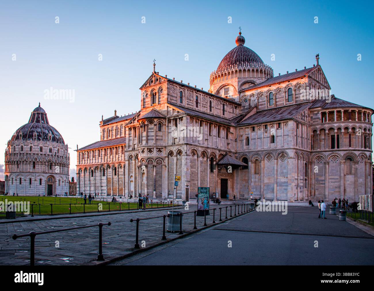 Goldenes Licht bei Sonnenuntergang taucht die Piazza dei Miracoli in Pisa auf und hebt den majestätischen Schiefen Turm und die Kathedrale in eine ruhige, zeitlose Atmosphäre hervor. Stockfoto