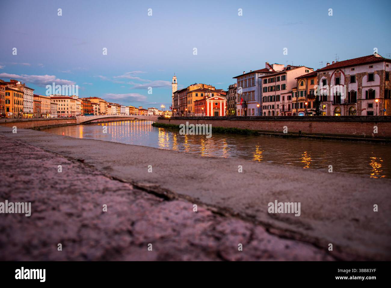 Urbane Szene bei Sonnenuntergang im Stadtzentrum von Pisa. Die Lungarni glänzen sanft an einem typischen Frühlingsabend. Stockfoto