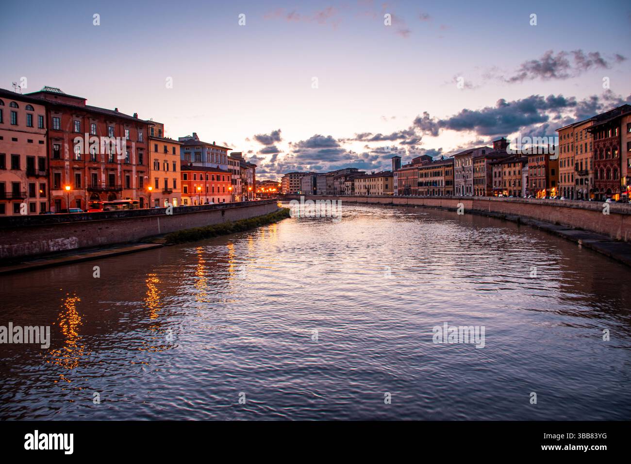 Urbane Szene bei Sonnenuntergang im Stadtzentrum von Pisa. Die Lungarni glänzen sanft an einem typischen Frühlingsabend. Stockfoto