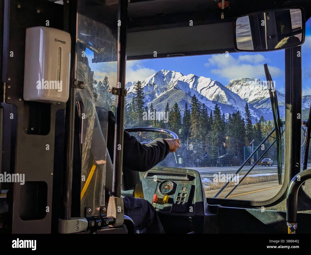 Ein nicht erkennbarer Busfahrer, der einen Shuttlebus auf der Autobahn in den Bergen betreibt – Blick von innen. Transport in den Bergen. Berufskonzept Stockfoto