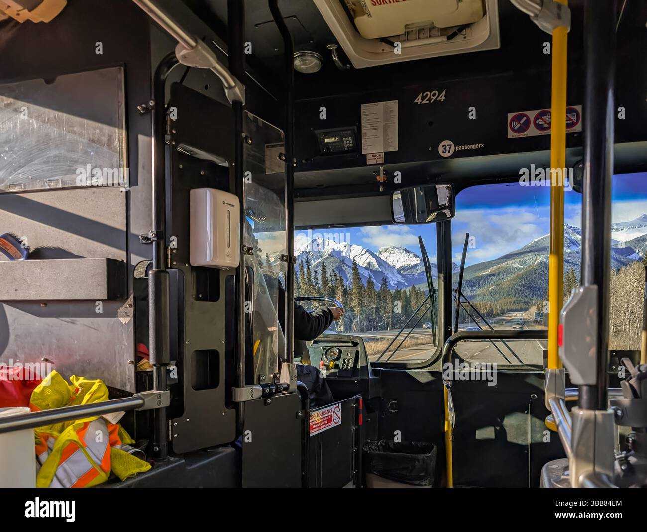 Ein nicht erkennbarer Busfahrer, der einen Shuttlebus auf der Autobahn in den Bergen betreibt – Blick von innen. Transport in den Bergen. Berufskonzept Stockfoto