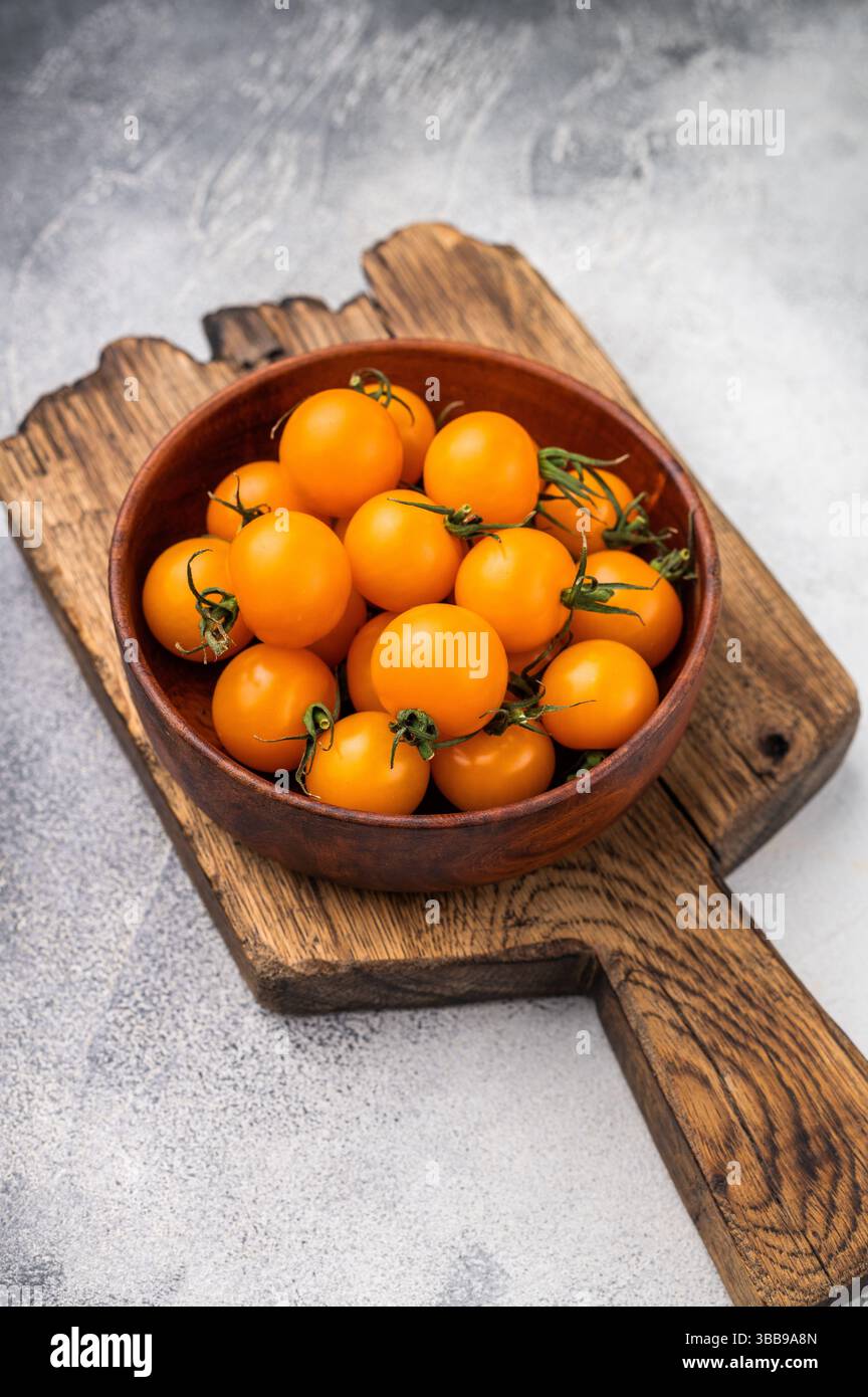 Frische kleine gelbe Kirschtomaten-Sortiment, Mini-Bio-Cocktail-Tomatenmischung. Grauer Hintergrund. Draufsicht. Stockfoto