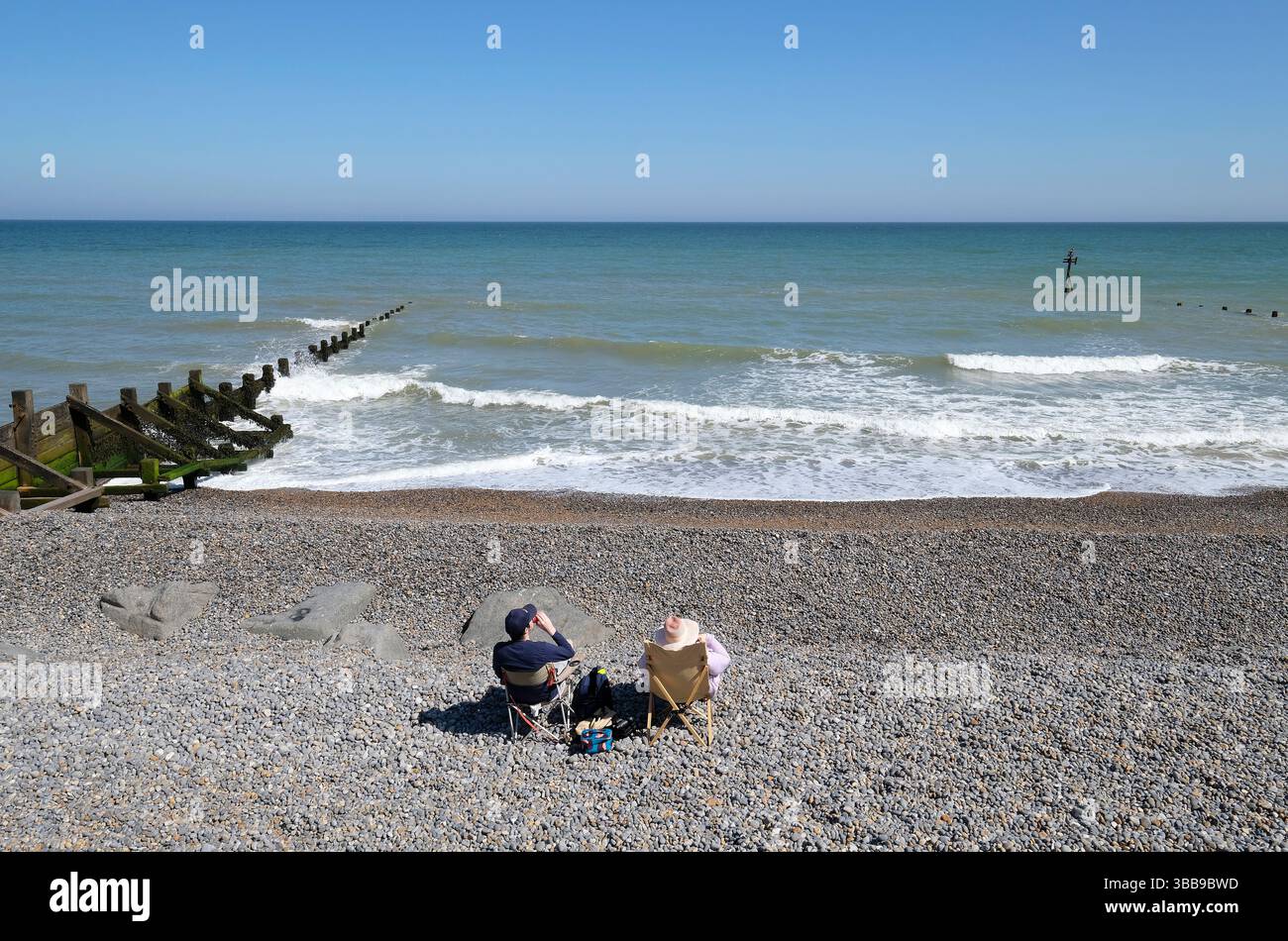 Leute, die am sheringham Shingle Beach im Norden norfolk, england sitzen Stockfoto