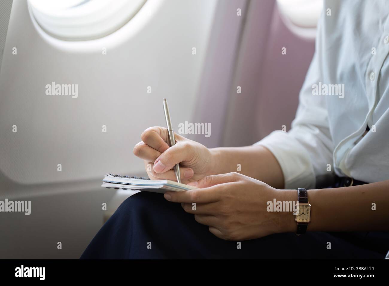 Geschäftsreisen. Professionelle Frau, die Notizen macht, während sie in einem Flugzeug fliegt. Stockfoto
