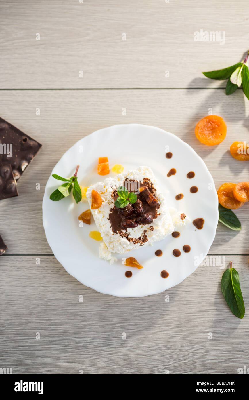 Süßes Hüttenkäse-Frühstück auf einem Teller mit Schokoladensirup und kandierten Früchten. Stockfoto
