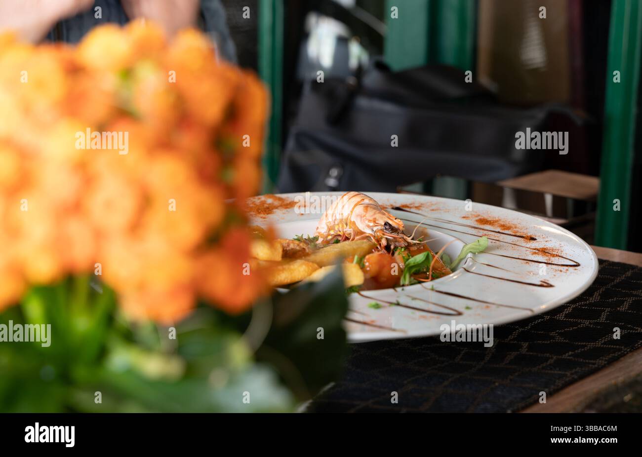 Ein wunderschön plattiertes und künstlerisch gestaltetes Fischgericht, das elegant sitzt und von einem lebhaften Blumendekor umgeben ist Stockfoto