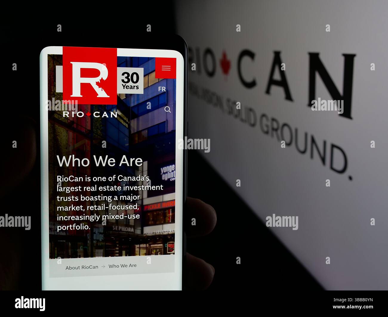 Stuttgart, Deutschland - 01-02-2024: Person, die ein Mobiltelefon hält, mit Website der Firma RioCan Real Estate Investment Trust auf dem Bildschirm mit Logo. Stockfoto