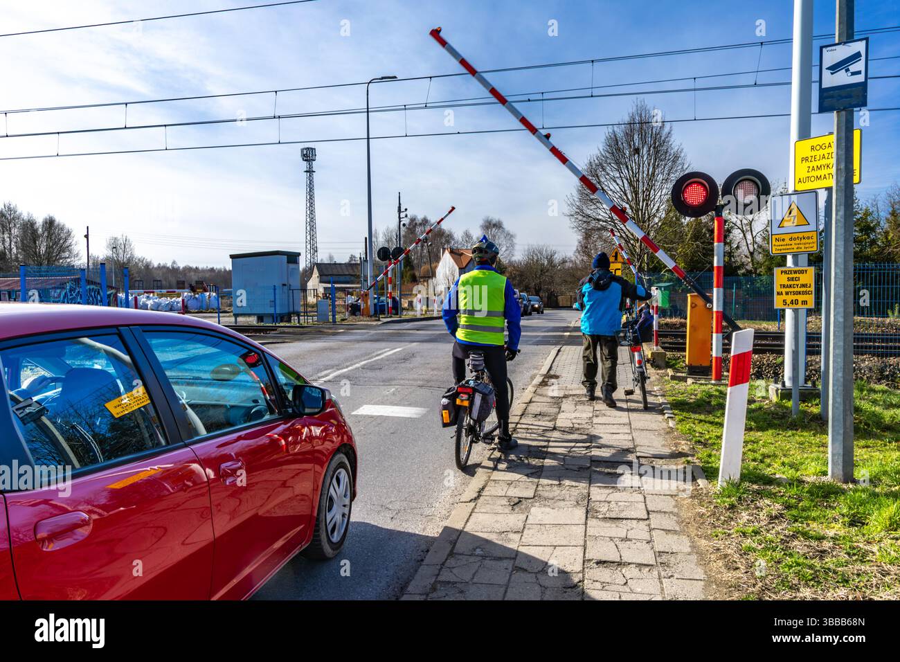 Radfahrer, der vor einer geschlossenen Schranke an einem Bahnübergang wegläuft, rote Warnleuchte kein Einstieg in die Bahngleise Stockfoto
