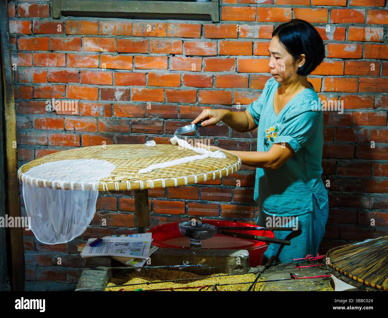 Eine Frau schneidet Reispapier in kleine Stücke, um Toffee, CA bei, Vietnam, einzuwickeln Stockfoto