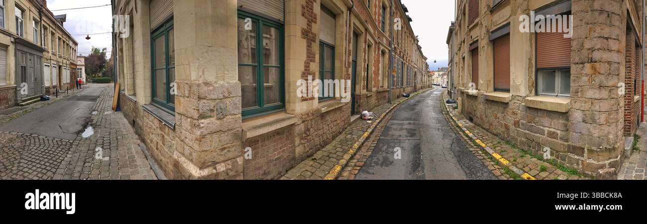 Ein fesselndes Panoramabild mit einer leeren gepflasterten Gasse, die von bezaubernden historischen Gebäuden gesäumt ist und architektonische Details in Ruhe zeigt Stockfoto