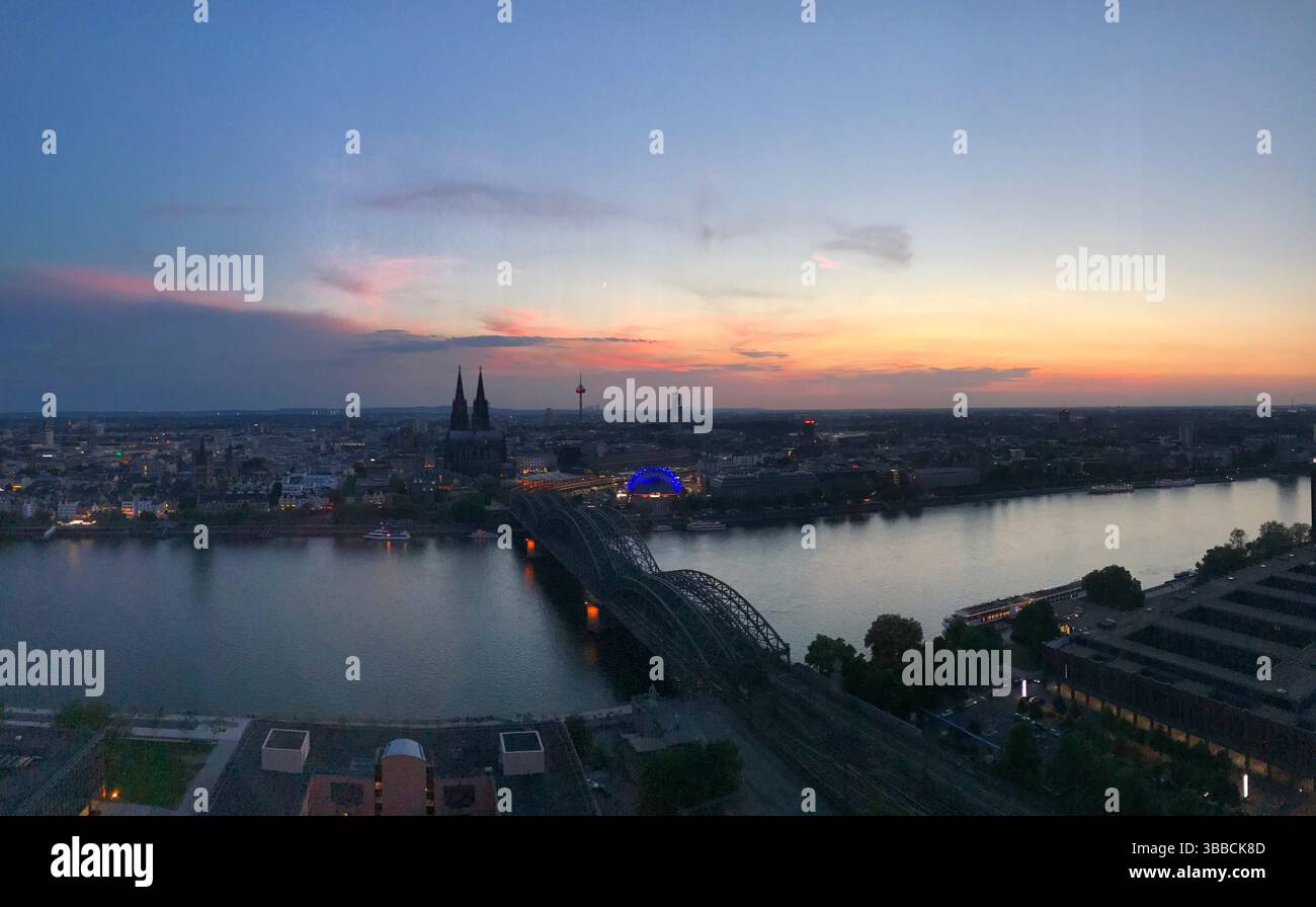 Ein atemberaubendes Panorama von Köln bei Sonnenuntergang, mit Blick auf den Rhein und den berühmten Dom mit seinen Zwillingstürmen, die eine wunderschöne Mischung aus Natur bieten Stockfoto