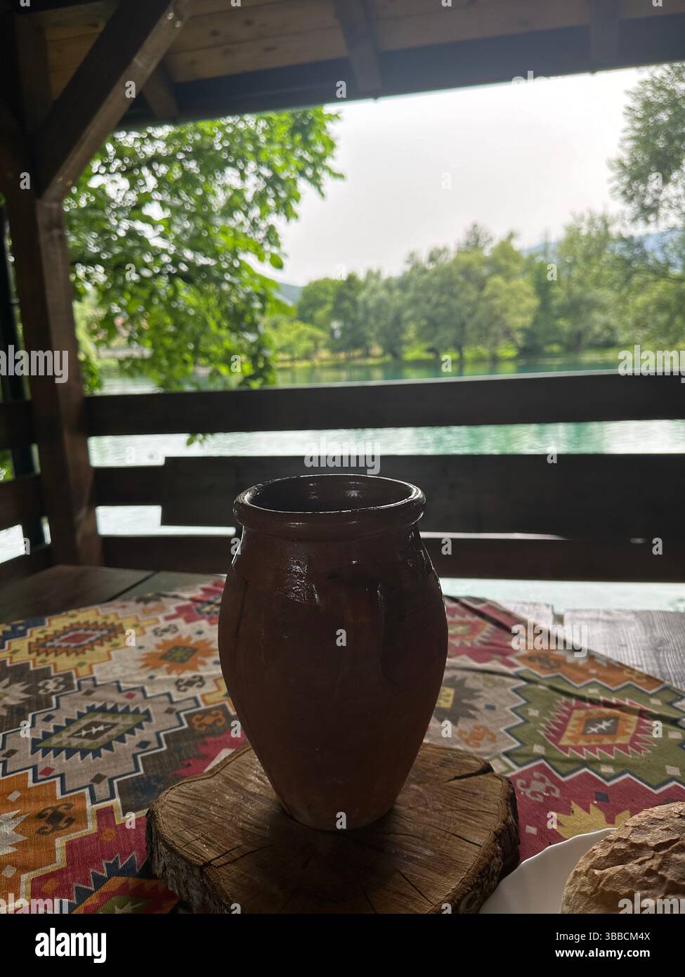Tontopf auf einem Tisch mit malerischem Blick auf Bäume und Hügel von einem Balkon in Bosnien und Herzegowina. Mit Liebe. - Smartphone-aufgenommenes Stockfoto