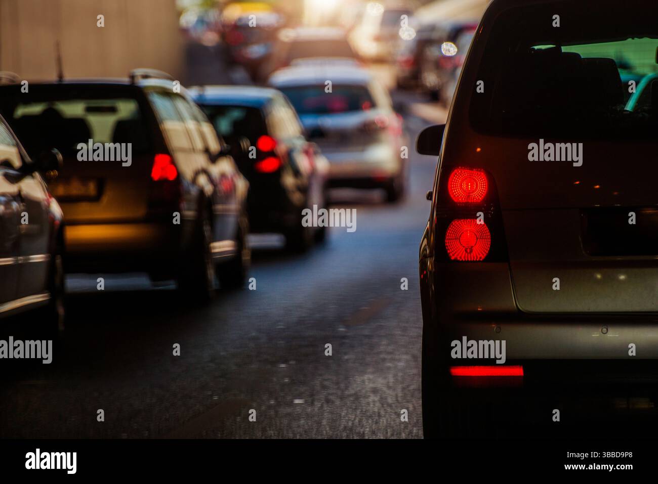 Wenn die Sonne untergeht, fahren die Fahrzeuge langsam durch einen Stadttunnel, wodurch ein Stau entsteht, der typisch für die Hauptverkehrszeit ist. Das warme Leuchten der untergehenden Sonne leuchtet Stockfoto