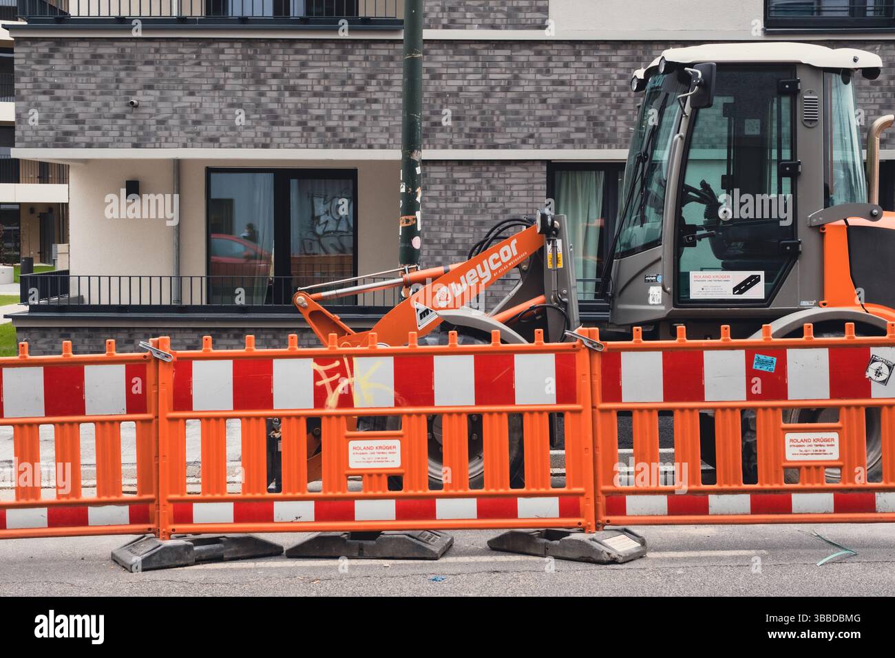 Bautraktor vor neu erbauten Wohnungen in der Gerresheimer Straße Stockfoto