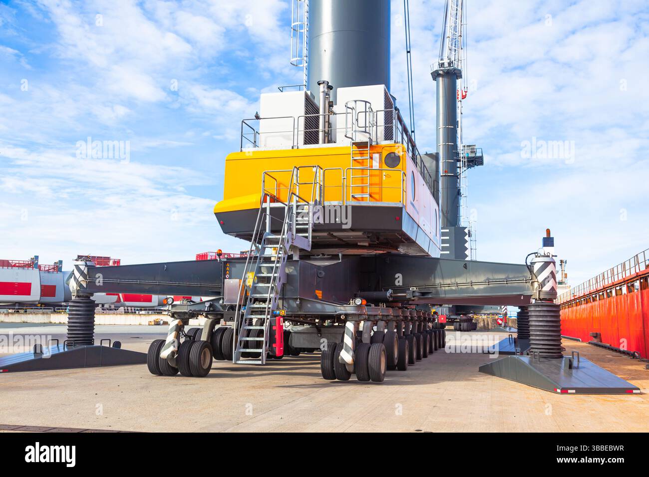 Großer Lkw-Kran steht auf Stützen im Seehafenbereich und einsatzbereit. Stockfoto