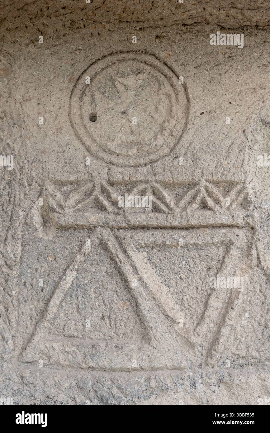Geometrische Schnitzereien und christliche Symbole sind in die weichen Steinmauern der Yusuf Koc Kirche eingeätzt, die in Kappadokien felsigem Gelände zu finden ist. Stockfoto